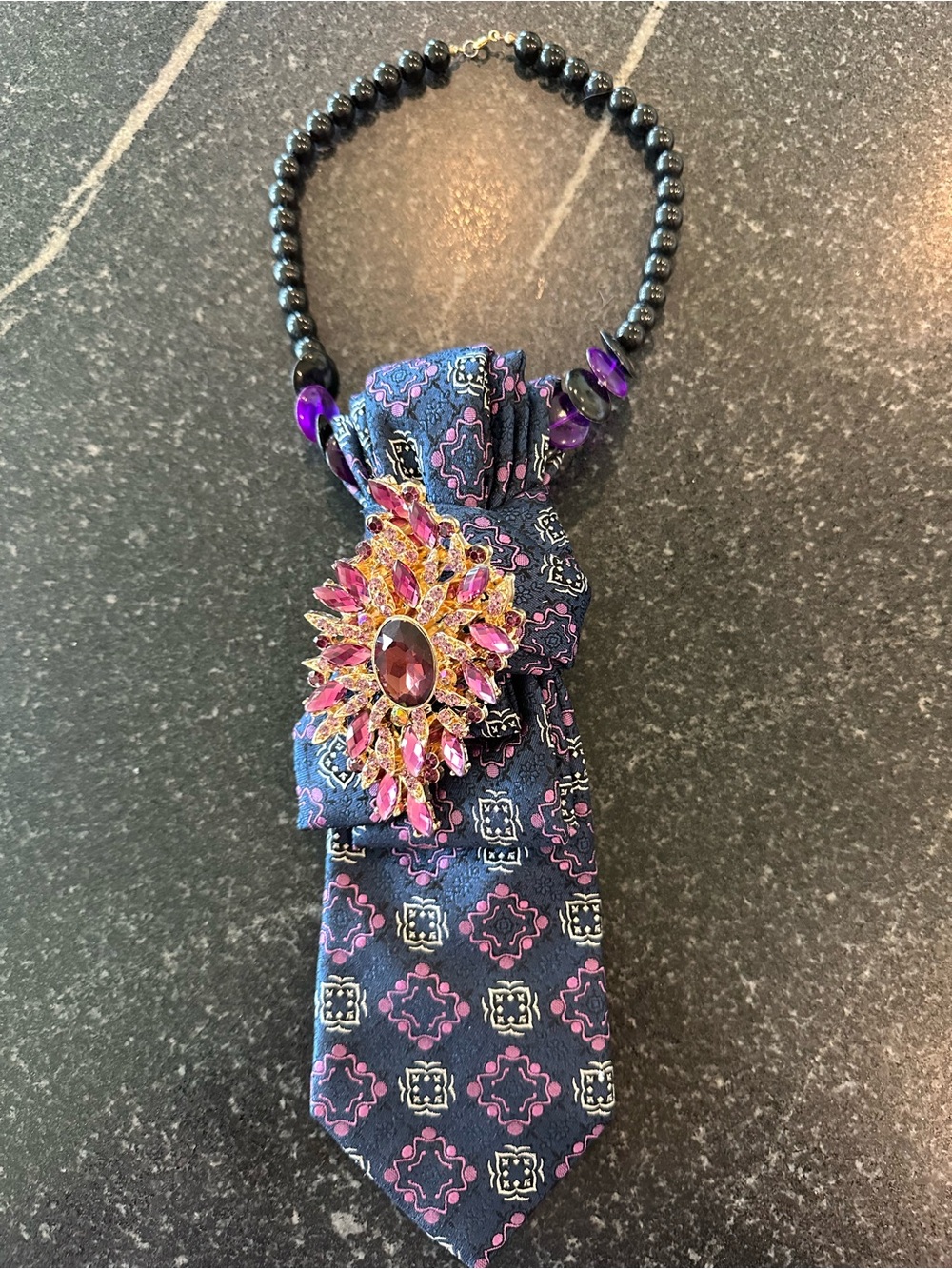 Navy Blue Patterned Tie Necklace with Pink Gem Brooch  on black beads.